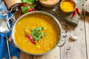 Indian food, a real Indian dish. Traditional Indian spicy lentil puree soup with herbs on a rustic table. Copy space.