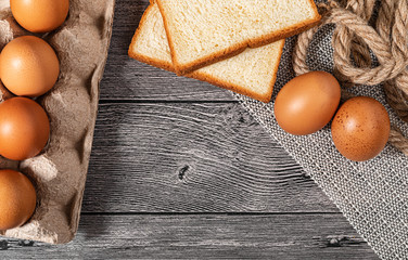 Top view bread and eggs is in paper trays put on wooden floor background and copy space for text