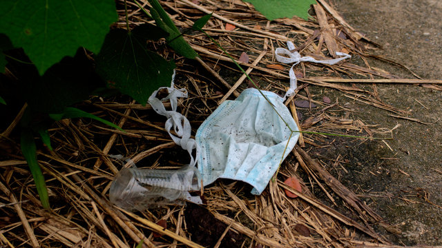 Used Blue Cloth Face Mask Dumped On The Street Among The Trash