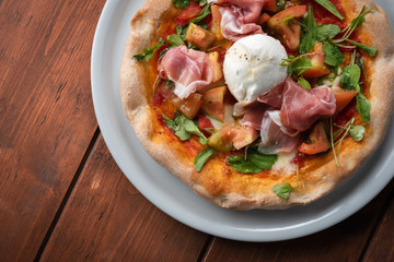 Deliziosa pizza primavera con prosciutto crudo, mozzarella fior di latte, rucola, sugo e pomodoro fresco