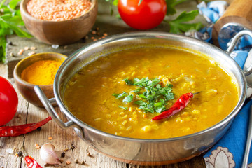 Indian food, a real Indian dish. Traditional Indian spicy lentil puree soup with herbs on a rustic table.