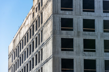 Corner of a monolithic building poured from concrete with windows.