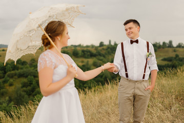 The groom holds the bride by the hand at wedding against the backdrop of a beautiful landscape