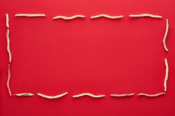 Italian fileja pasta on a red background. Pasta shaped into rectangle frame. Flat lay photo
