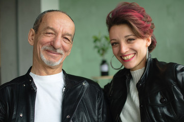 Emotional family portrait of adult daughter and senior father in loft room with houseplants....