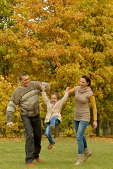 Naklejka na ściany i meble Happy smiling family relaxing in autumn park