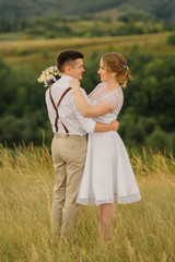 newlyweds in love are hugging and looking at each other against a background of beautiful green nature