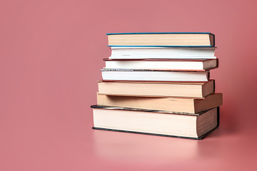 Books stacked on a pink background with copy space.