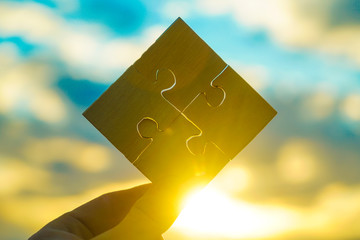Businessman hand cube from puzzle pieces into a single unit on sunset background. The idea of a business concept, teamwork, cooperation, partnership, creative