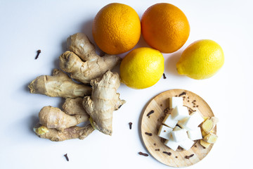 Fruit. Ginger orange lemon and lumps of sugar on a wooden saucer, all on a white background.