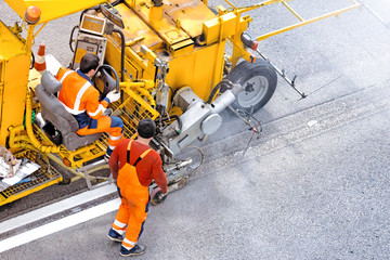 road worker at construction work on street against asphalt surface background Top down view of road markings painting process Modern highway surface repair equipment at work
