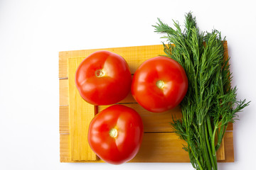Tomatoes and dill lie on a cutting Board on a white background.