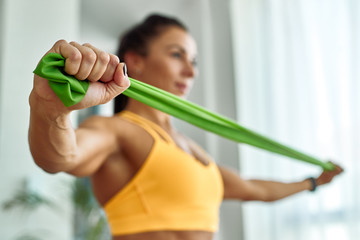 Close-up of athletic woman exercising with resistance band at home.