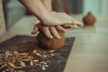 A man wrinkles clay with his hands. Work on the pottery wheel. The master is preparing clay.