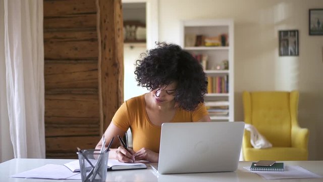 mixed race female student making notes in notebook using laptop Spbd. teen girl woman prepare to lesson. self education online, homework concept. distance studying while staying at home