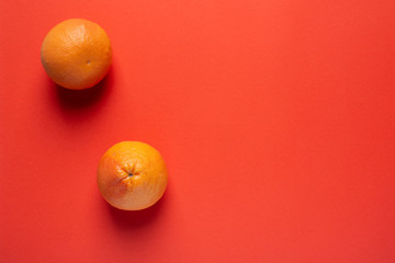 Abstraction with two whole grapefruits on a coral background.