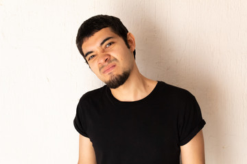 Young short-haired Hispanic man with black clothes, angry, furious, upset, stressed posing on a white background
