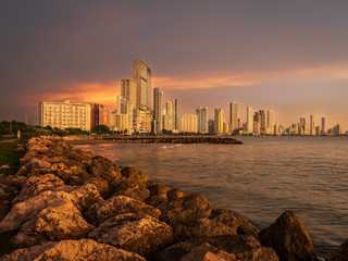 Fototapeta premium Sunset over a coastal city with skyscrapers along the coastline 