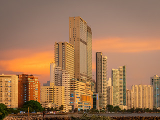 Fototapeta na wymiar Sunset over a coastal city with skyscrapers along the coastline 