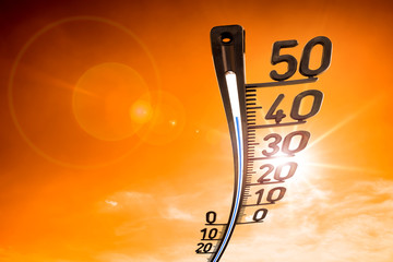 Thermometer on orange sky with bright sun as a symbol for climate change