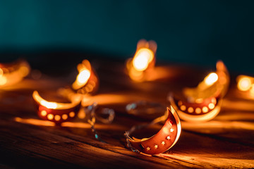 Ramadan Moon with Colorful Light Glowing at Night and Glittering with Bokeh Lights on Ground. Festive Greeting Card, Muslim Holy Month Ramadan Kareem. Blue Dark background. Ramadan Crescent / New Moon