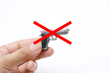 Red Cross Sigh Forbidden, Hand Holding Tiny Model Automatic Gun on White Background, Stop Gun Violence, No Have Victim                                                                                 