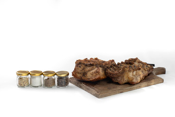 cutting Board with baked ribs and jars of spices: salt, pepper,fennel, cumin. baked ribs for a cookbook. grilled ribs for the restaurant menu.