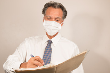 Doctor/Healthcare worker wearing a surgical mask checking over his patients reports