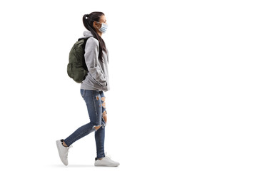 Naklejka premium Casual female student wearing a protective medical mask and walking