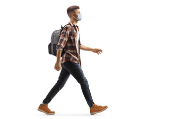 Young guy with a backpack wearing a protective medical mask and walking