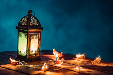 Ramadan Lantern with Colorful Light Glowing at Night and Glittering with Bokeh Lights on Ground. Festive Greeting Card, Invitation for Muslim Holy Month Ramadan Kareem. Blue Dark background
