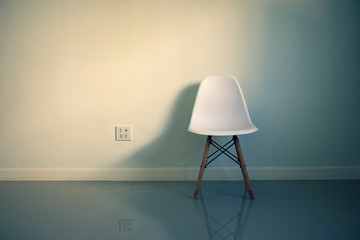 White chair with shadow and plug socket in a room at home,minimalistic style concept.