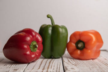 Pimiento ,morrón en tres colores, sobre base de madera vintage, color blanco