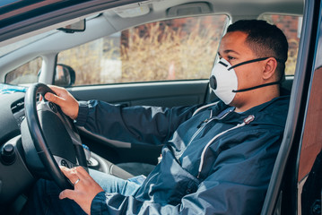 young hispanic man is in the car wears protective mask to prevent the spread of coronavirus.