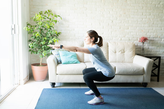 Active woman doing squats at home