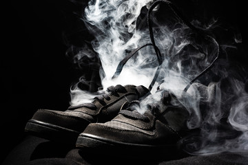 pair of worn out sneaker fuming. sports concept. black background