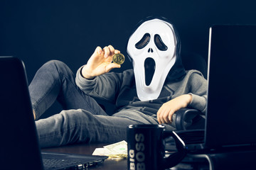 A hacker holds a bitcoin in his hand.
