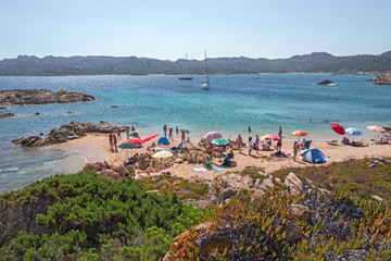 Fototapeta na wymiar Some swimmers tan on the sunny beaches of the island of Maddalena in Sardinia, Italy.