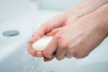 Hand washing with soap. Girl washes her hands with antibacterial soap for the prevention of coronavirus covid-19 2019-ncov and flu. Sink, faucet, hands and soap. Minimalist bathroom