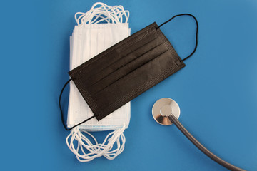 many white and one black protective antiviral medical masks, concept of the SARS-CoV-2 virus...