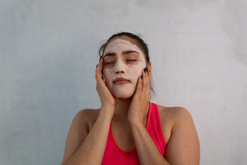portrait of young hispanic woman wearing a hydrating and exfoliating face mask on a white background