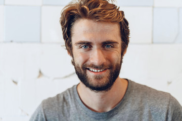 Close up Portrait of a young bearded man standing against grunge weathered wall