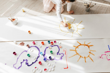 Cute happy little girl, adorable preschooler, painting with paints on paper roll