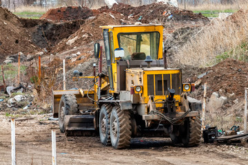 Obraz premium Yellow grader in a landfill