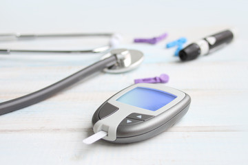 Digital glucometer and lancet pen, stethoscope, blood in vitro, on white background, concept of...