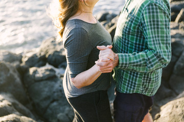 Middle aged couple embracing holding hands at ocean shore