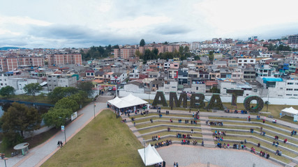 Aerial view of the buildings of the city of ambato in the central park of flowers. Panoramic view from a drone of the metropolis people walking and cars crossing and parked with vegetation and with ba