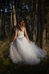 Fototapeta premium Beautiful girl with charming look with a white wedding dress in the forest