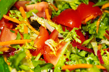 Vegetable salad sliced tomatoes, carrots, beets, lettuce, arugula and olives. Close-up background image.