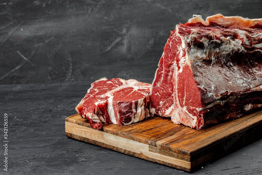 Wall mural Raw T-bone steak cooking on stone table.